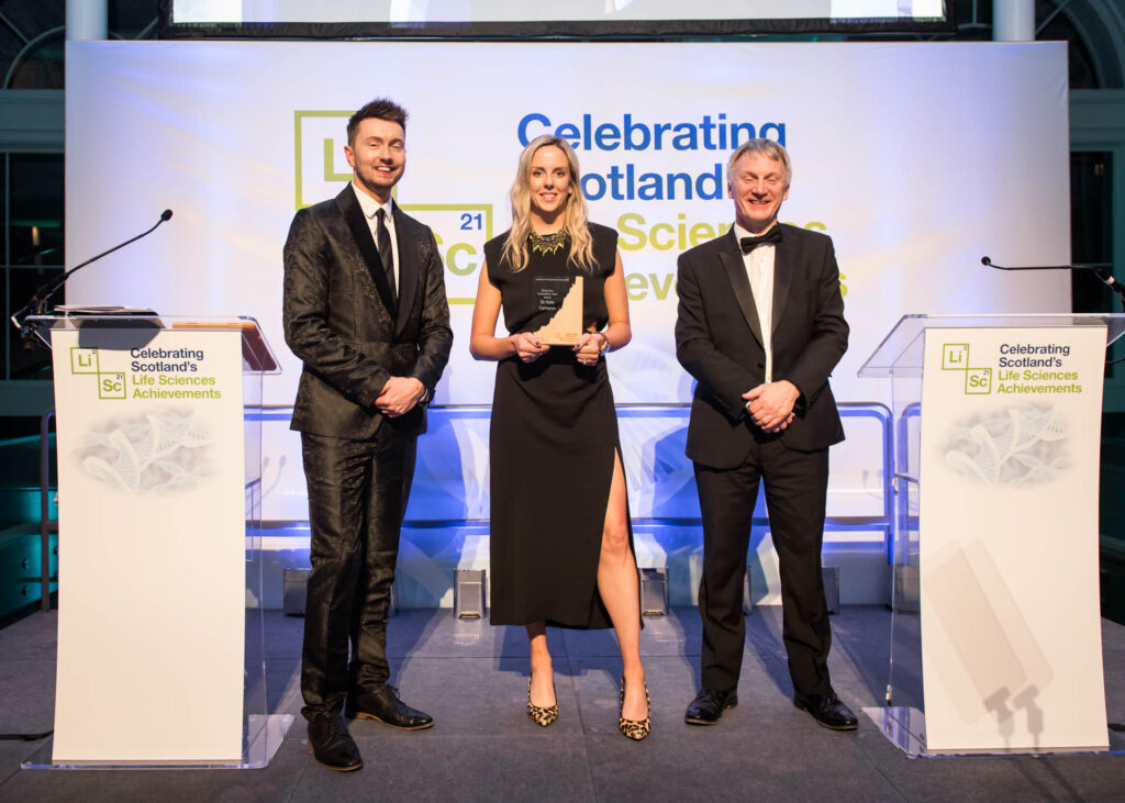 Image of Dr Kate Cameron accepting the Scotland's Life Sciences Rising Stars: Extraordinary Talent Award 2023 from from Minister Ivan McKee MSP the minister for Business, Trade Tourism and Enterprise and Sean Batty.